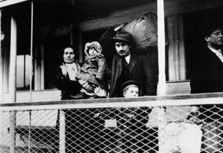 Early 20th century Italian immigrant family on ferry docking at Ellis Island, New York